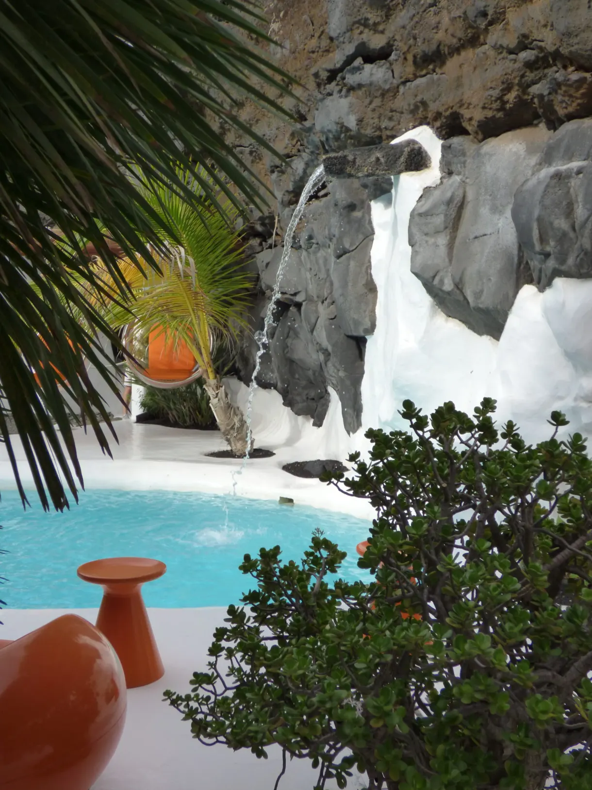 Jarres orange et bassin turquoise sous les palmes