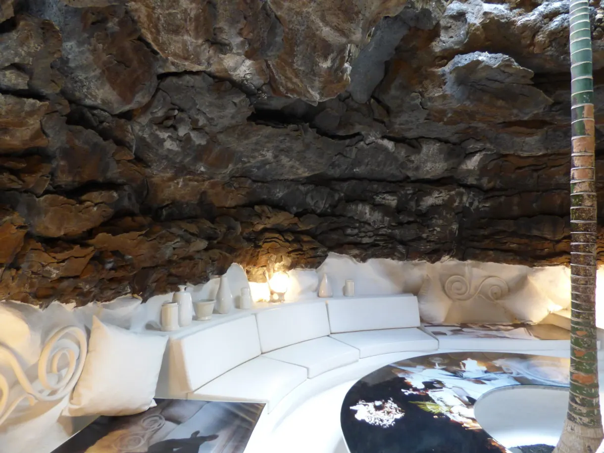 Salon blanc incurvé sous une voûte de roche volcanique