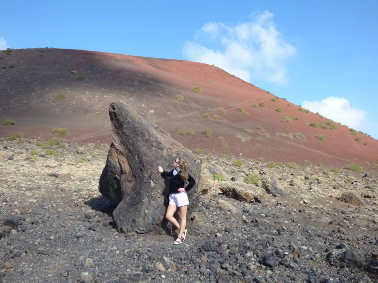 Femme adossée à une bombe volcanique devant la Montaña Colorada