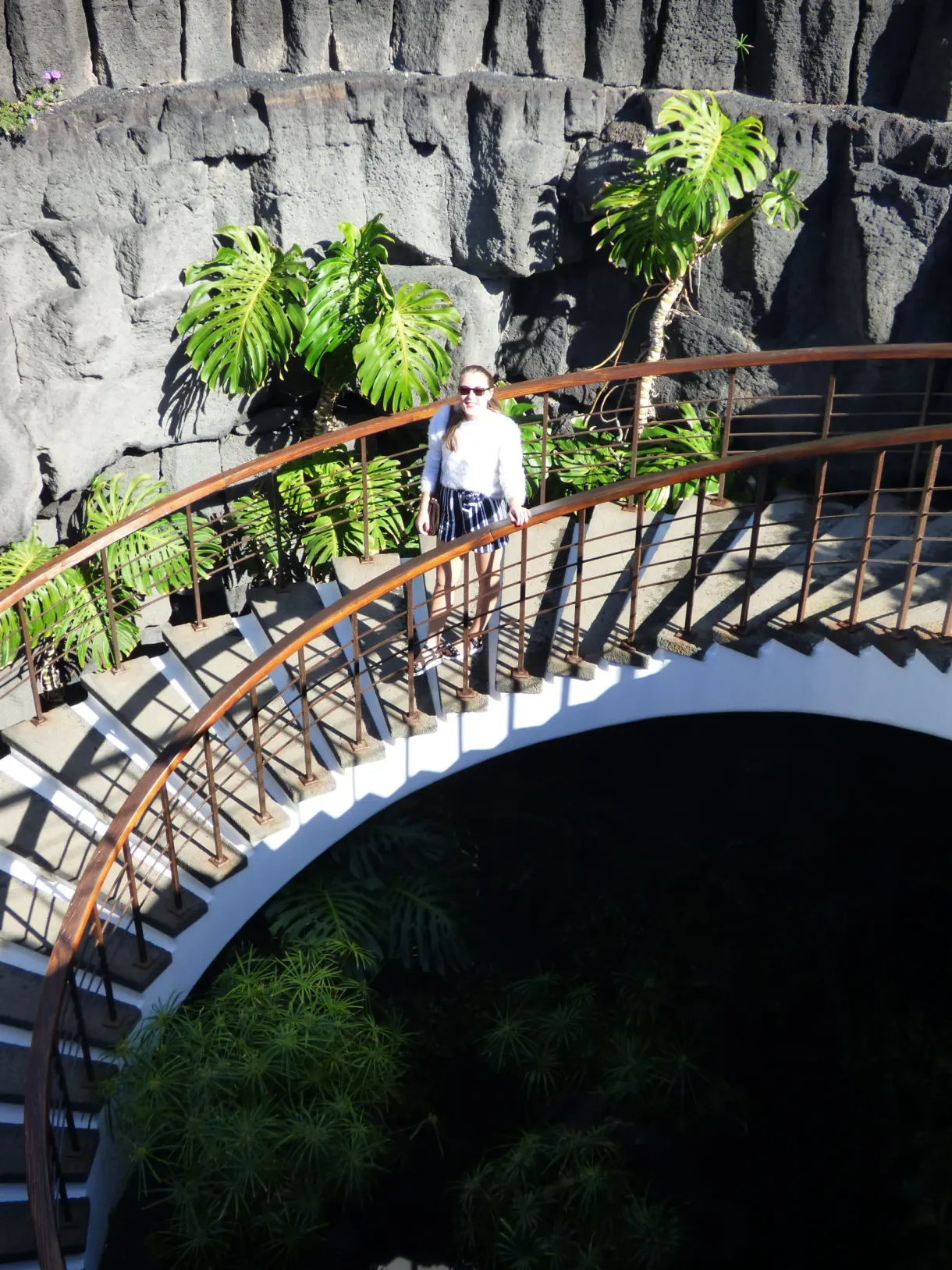 Passerelle courbe surplombant un patio creusé dans la roche