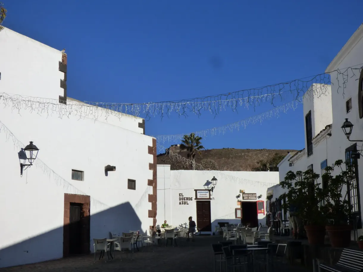 Terrasse de café dans une ruelle blanche sous les guirlandes
