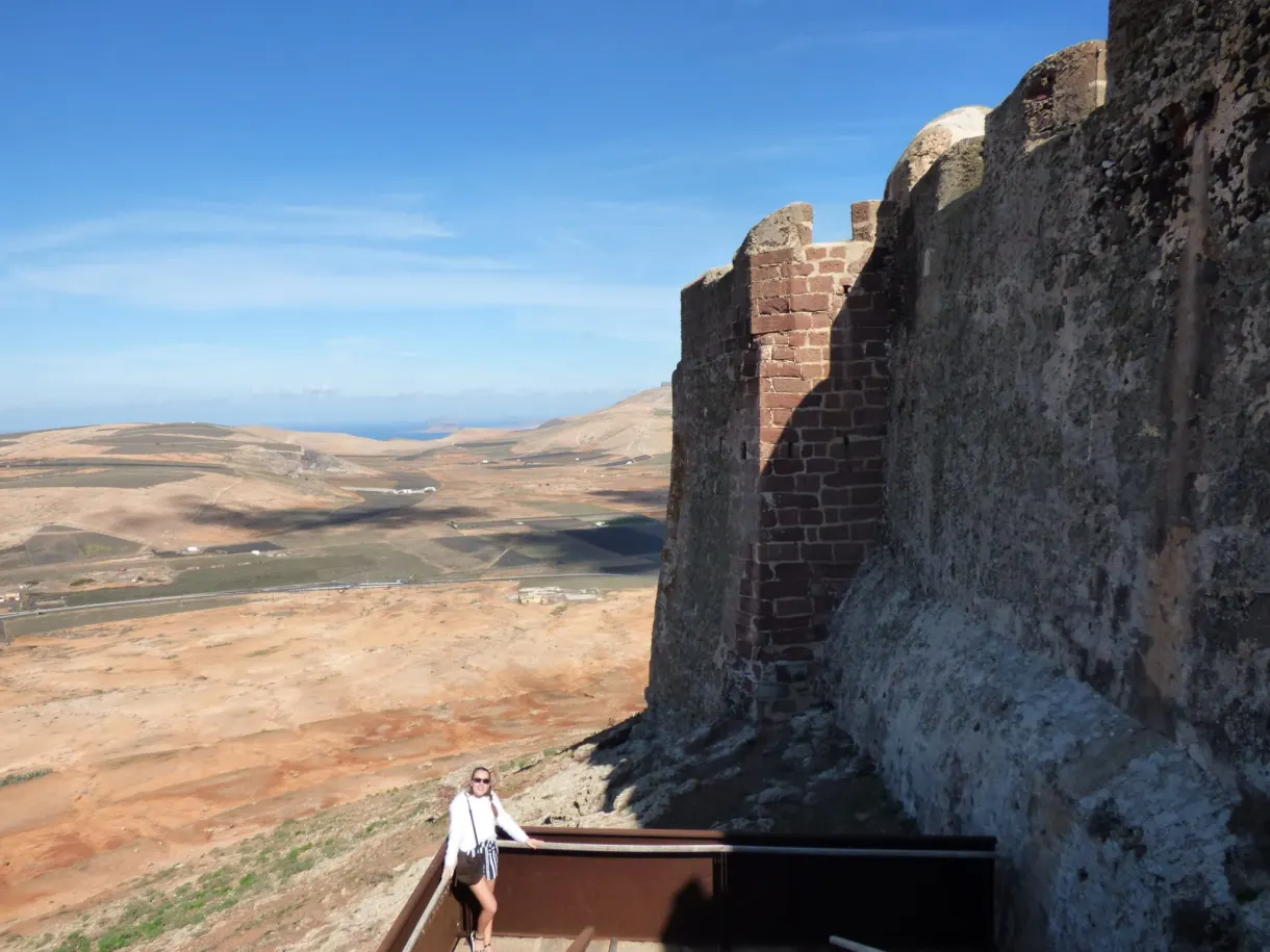 Femme assise au pied des remparts de pierre du château