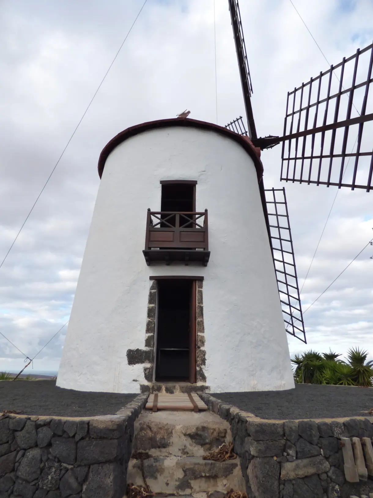 Moulin blanc aux ailes de bois sur un socle de pierre
