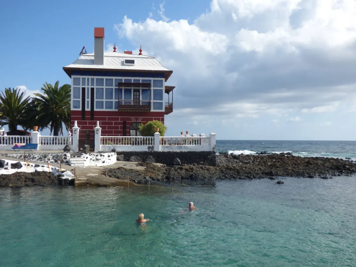 Maison rouge et blanche surplombant une piscine naturelle turquoise