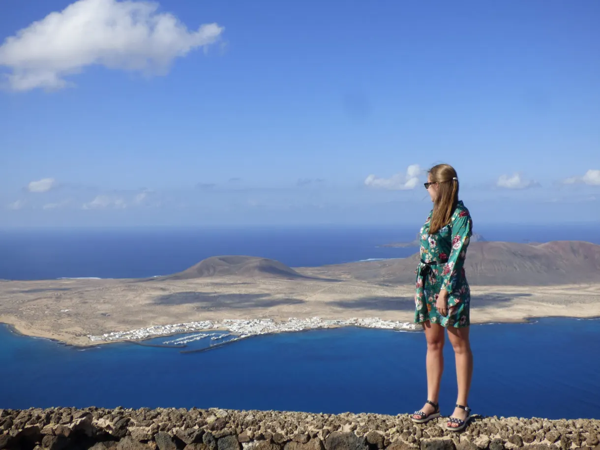 Femme en robe fleurie contemplant l'île depuis le belvédère