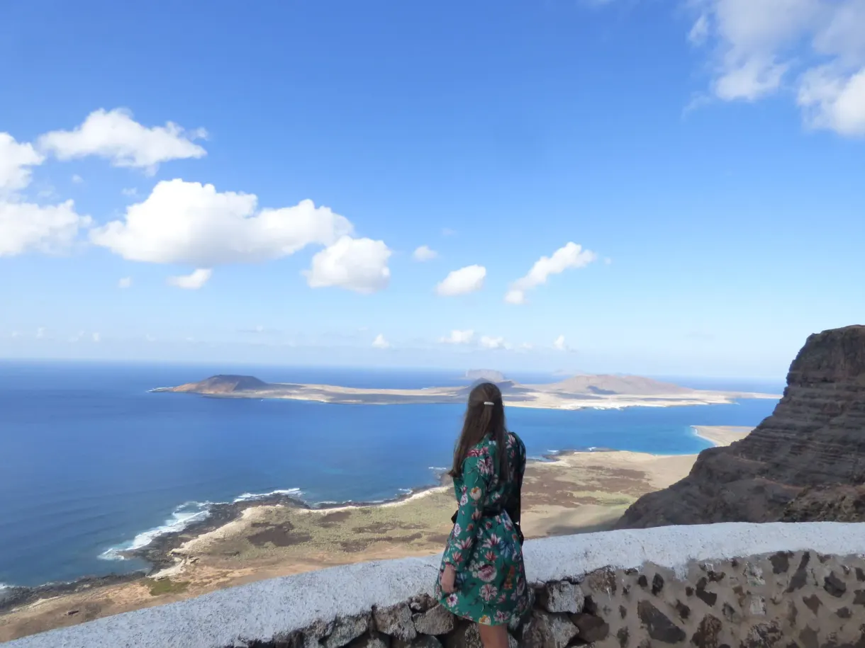 Femme de dos sur un muret blanc devant le bras de mer
