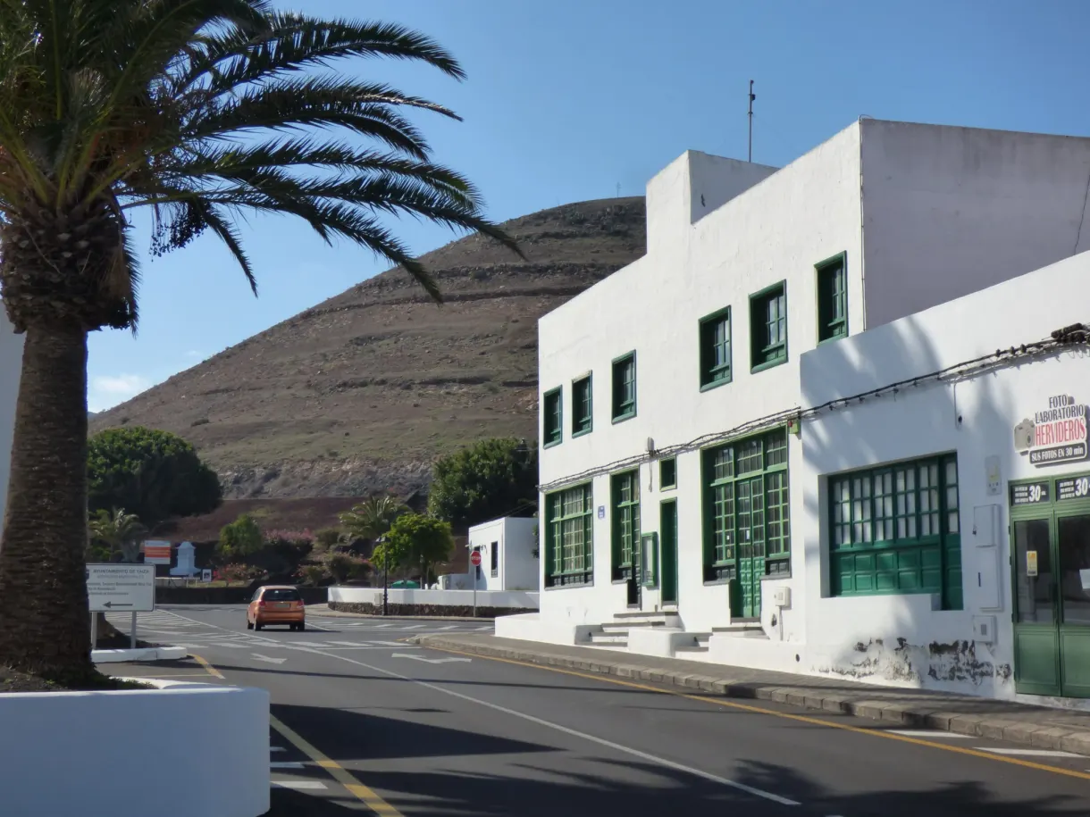 Bâtiment blanc aux volets verts au bord de la route de Yaiza