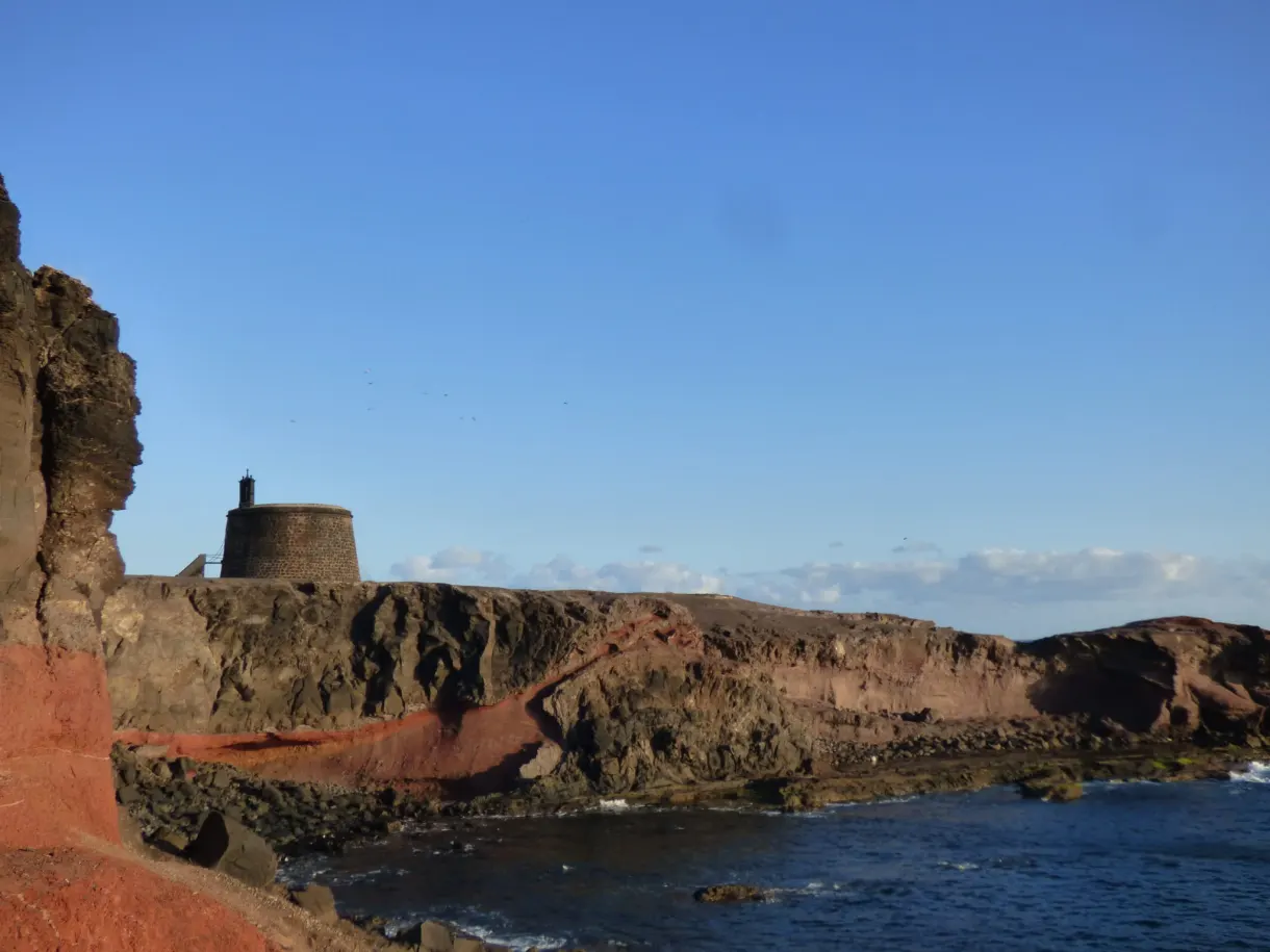 Tour de guet ocre au sommet d'une falaise rouge