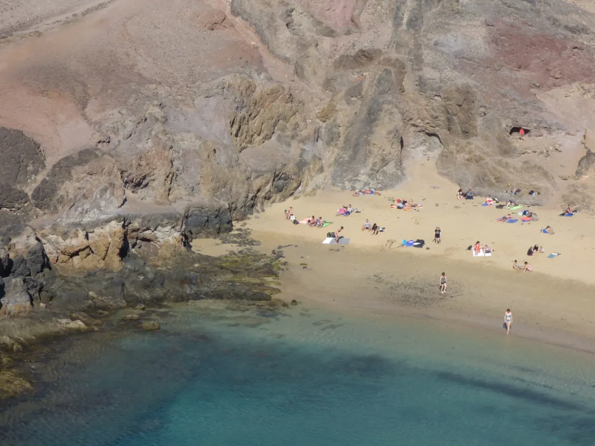 Crique encaissée entre falaises ocre, serviettes sur le sable