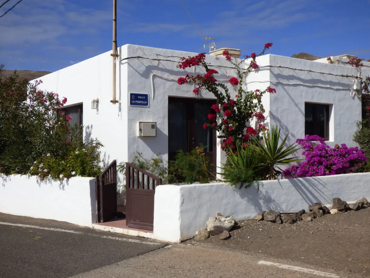 Maison blanche couverte de bougainvilliers rouges et roses