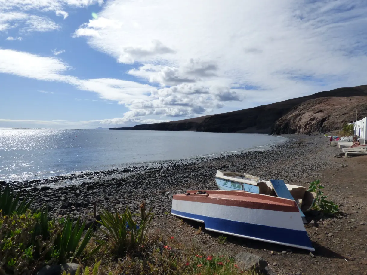 Barque bleue et blanche échouée sur la plage de galets