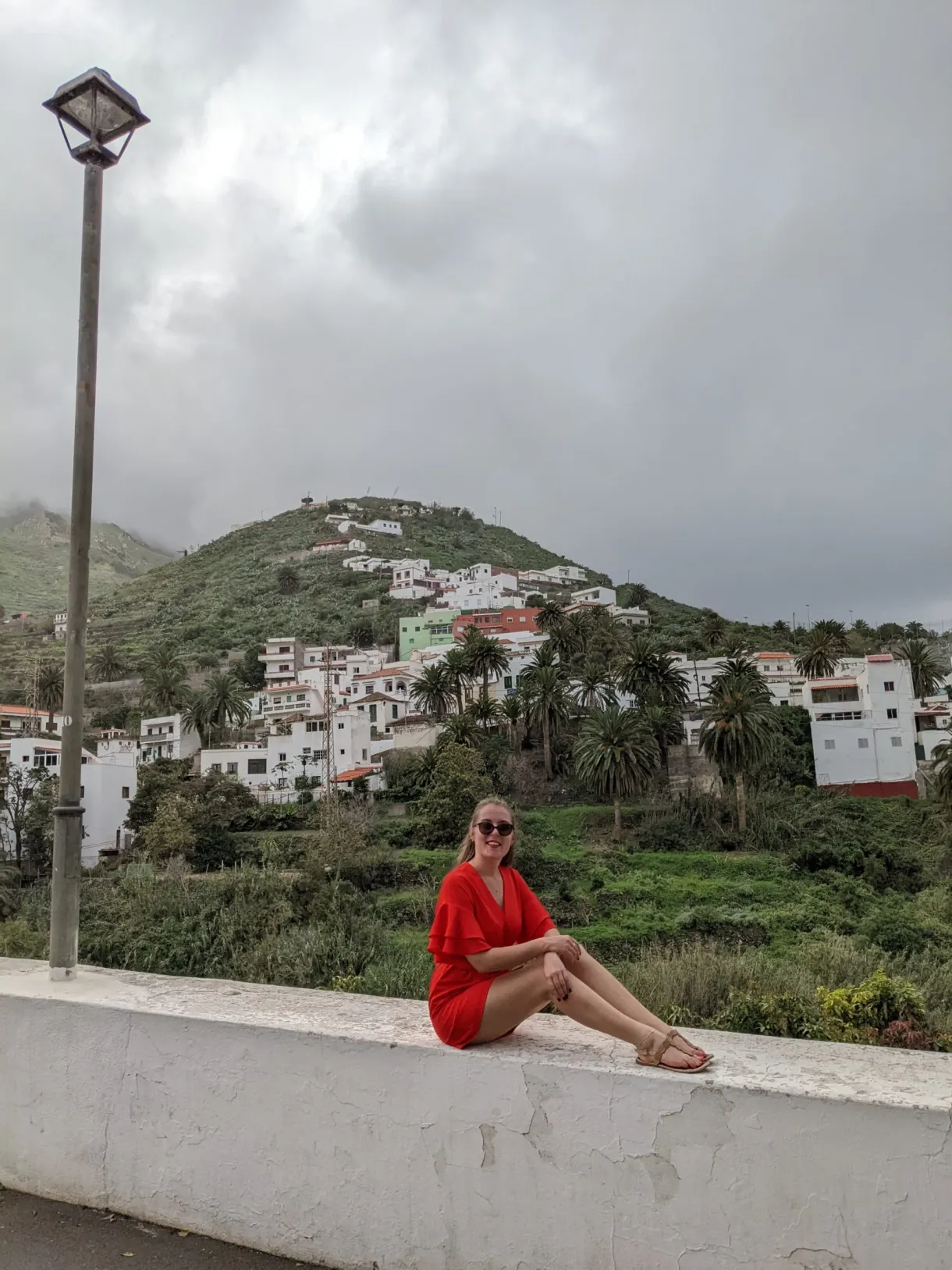 Femme en rouge assise sur un muret devant Taganana