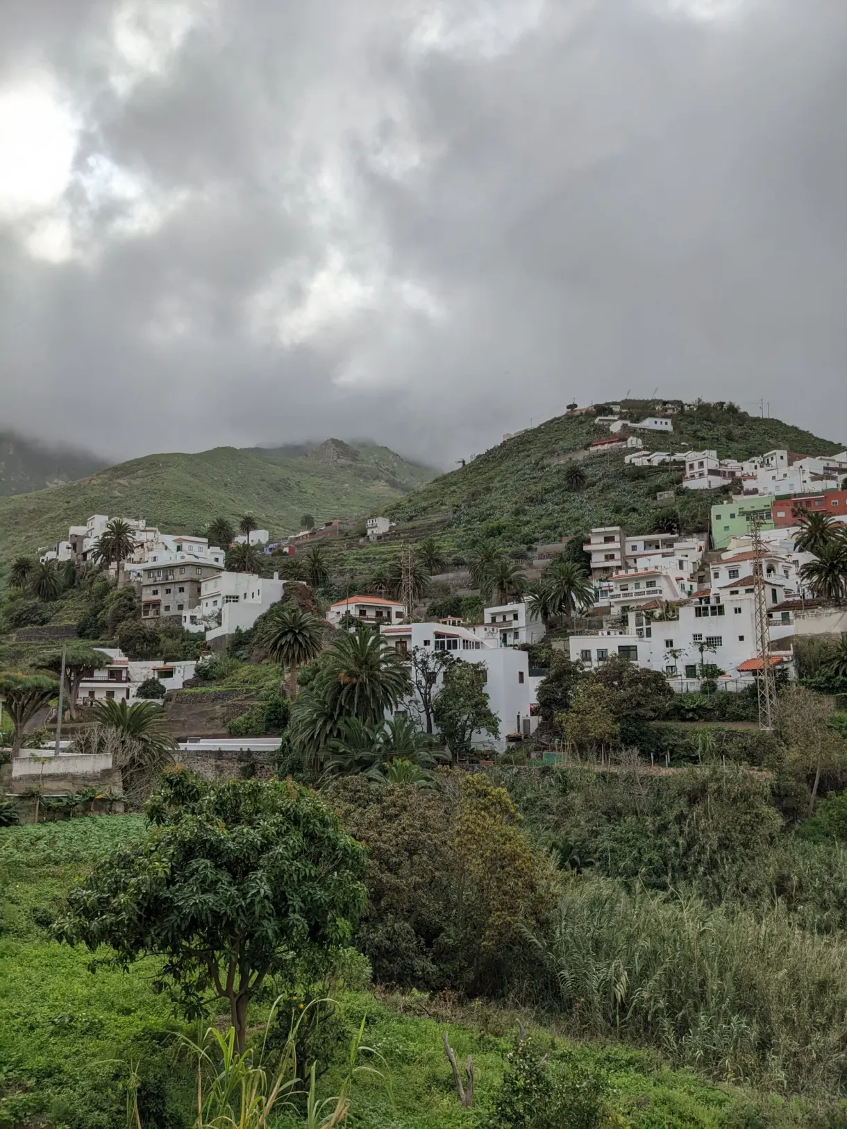 Maisons blanches accrochées à la colline sous les nuages