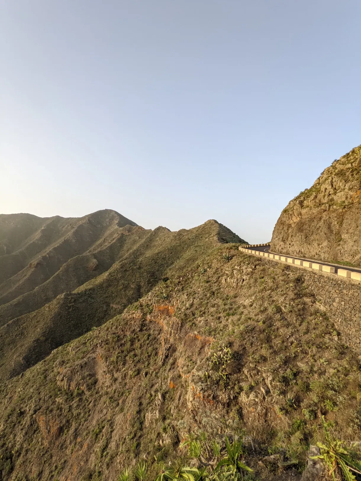 Route en corniche épousant une arête au coucher du soleil