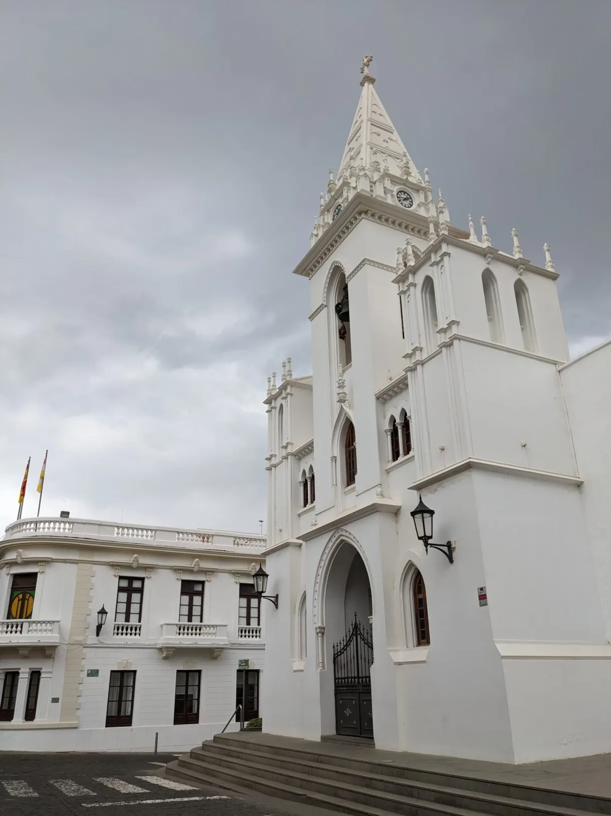 Église blanche et bâtiment à balcons sur une place pavée