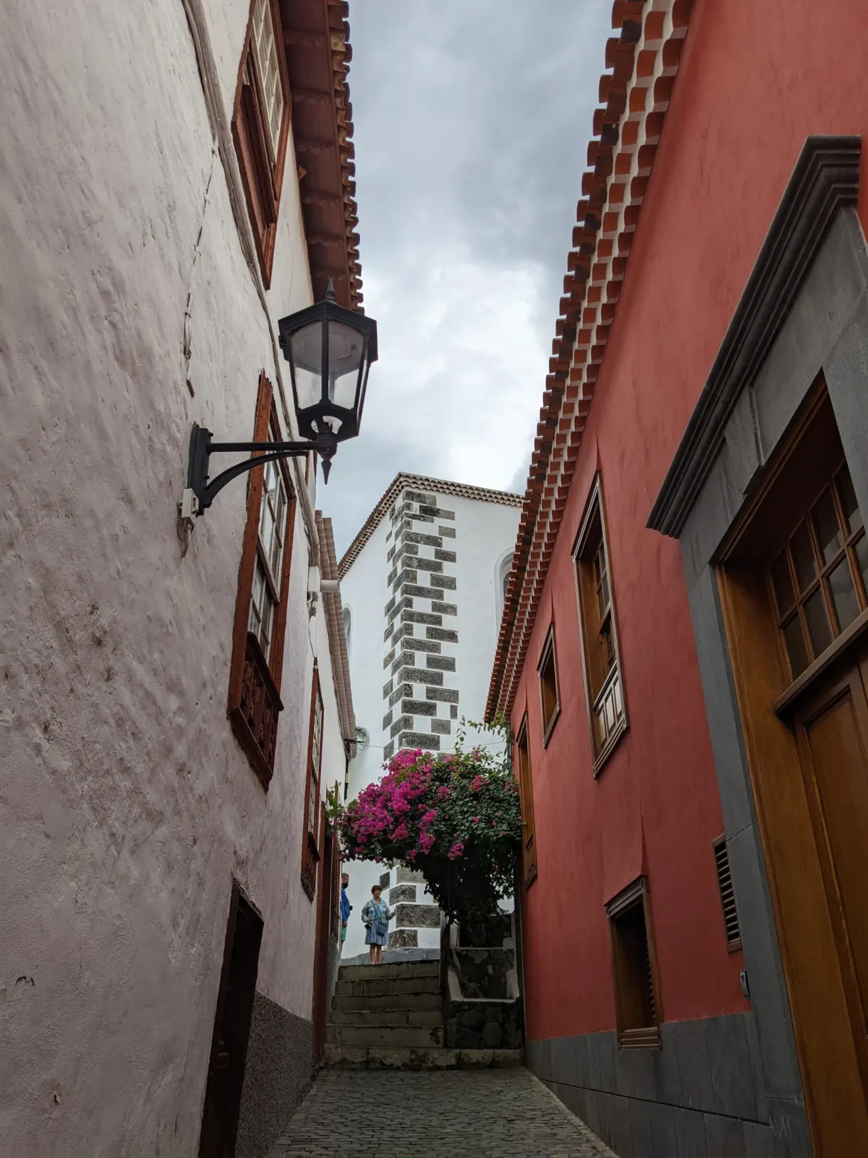 Ruelle étroite entre une façade rouge vif et un mur blanchi