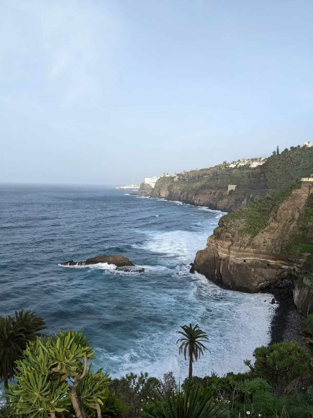 Falaises boisées et pointe rocheuse au-dessus d'une mer bleue