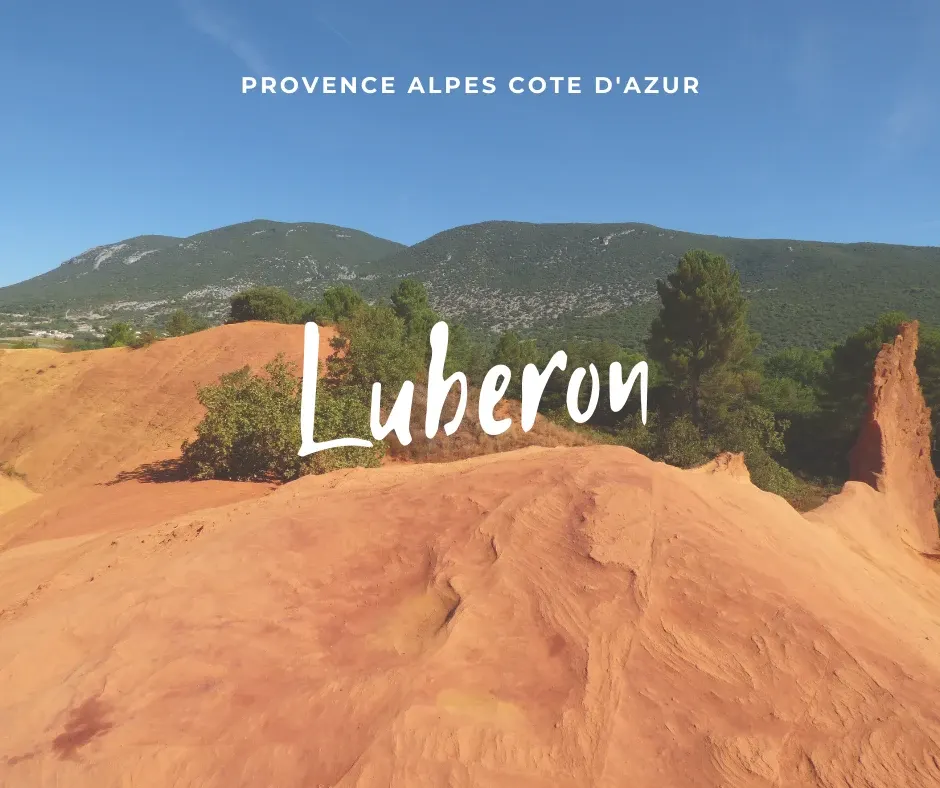 Orange ochre rocks in front of the wooded hills, title Luberon