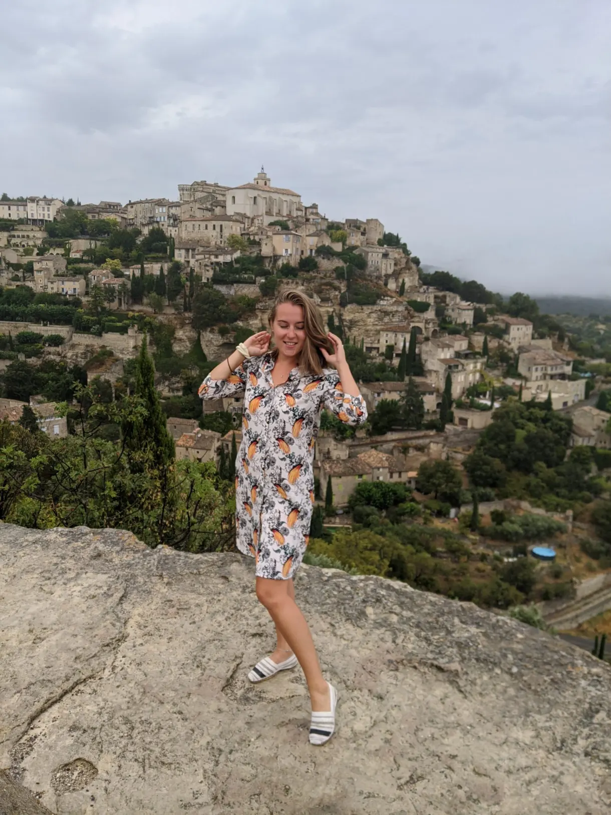 Woman posing on a rock in front of a hilltop village