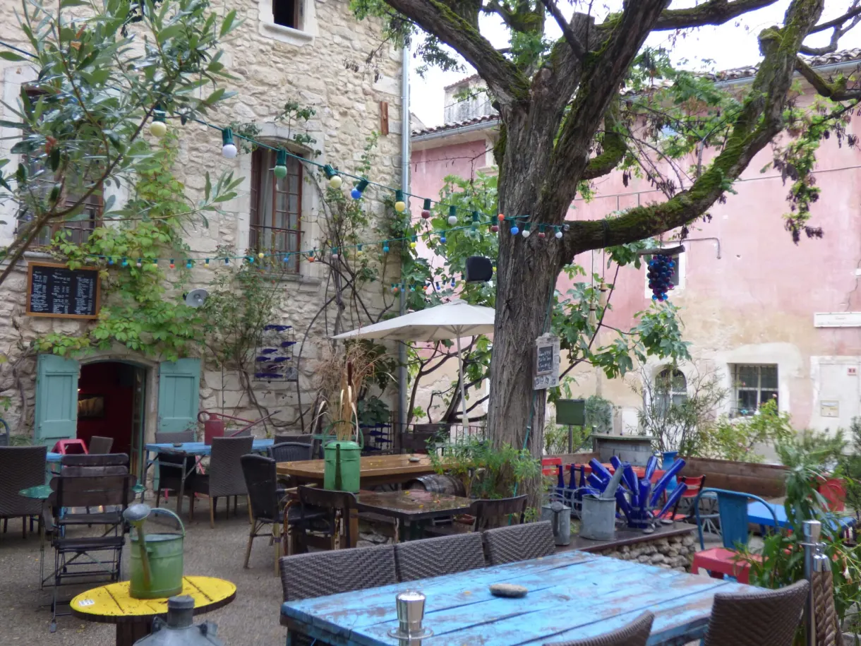 Café terrace with colourful tables beneath the plane trees