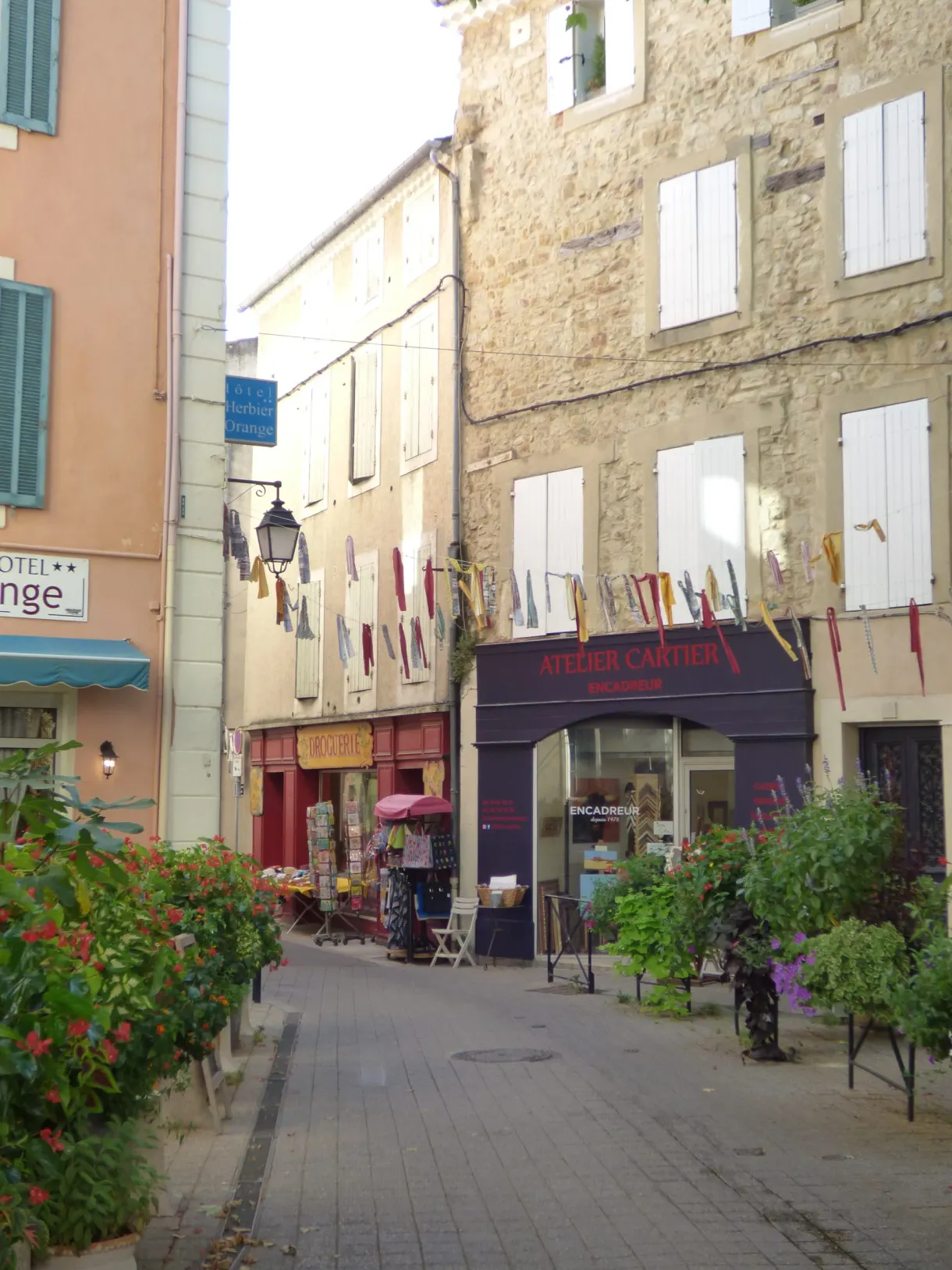 Rue commerçante pavoisée de fanions, volets blancs et boutiques