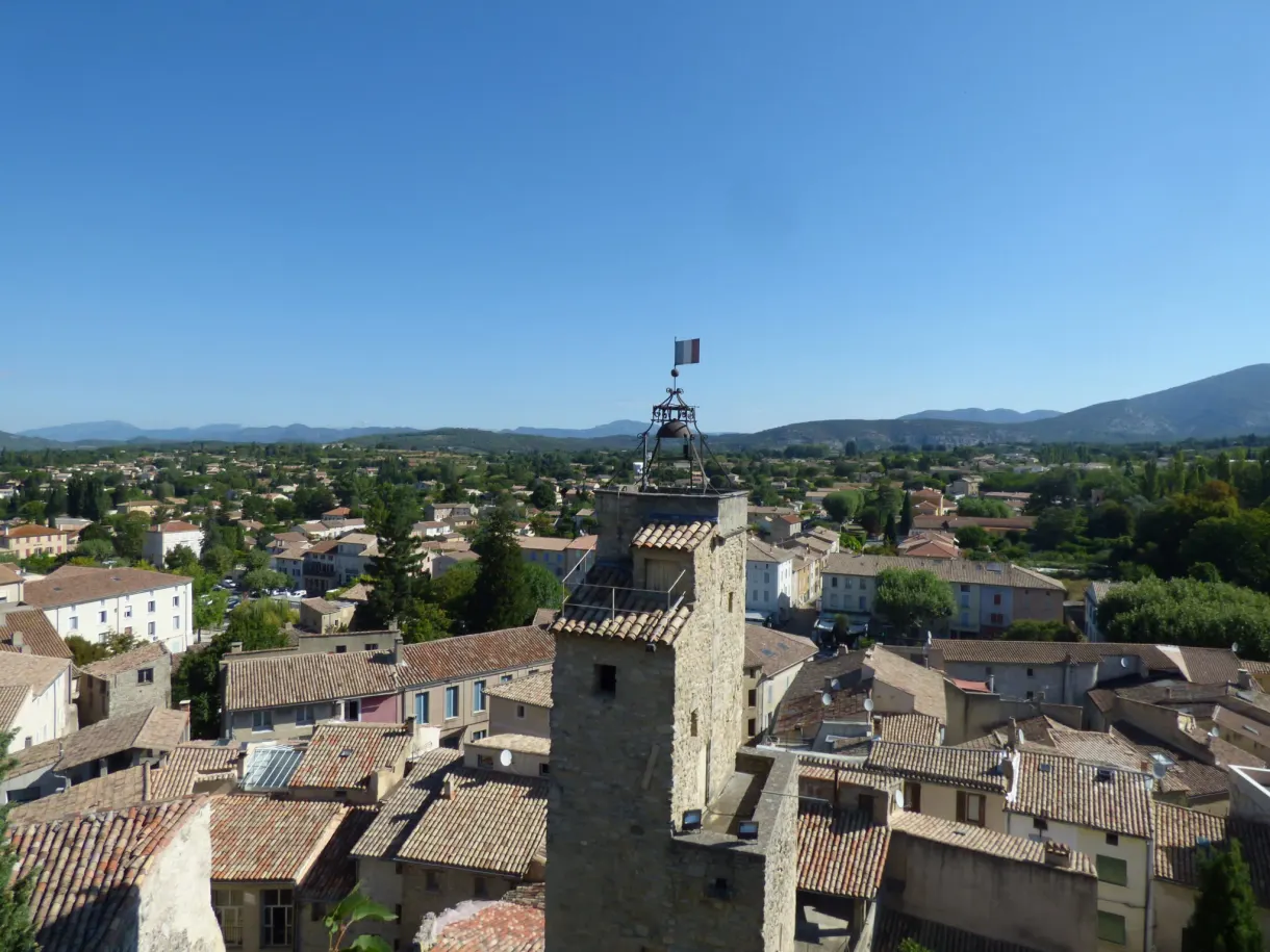 Clocher à campanile en fer forgé dépassant des toits de tuiles