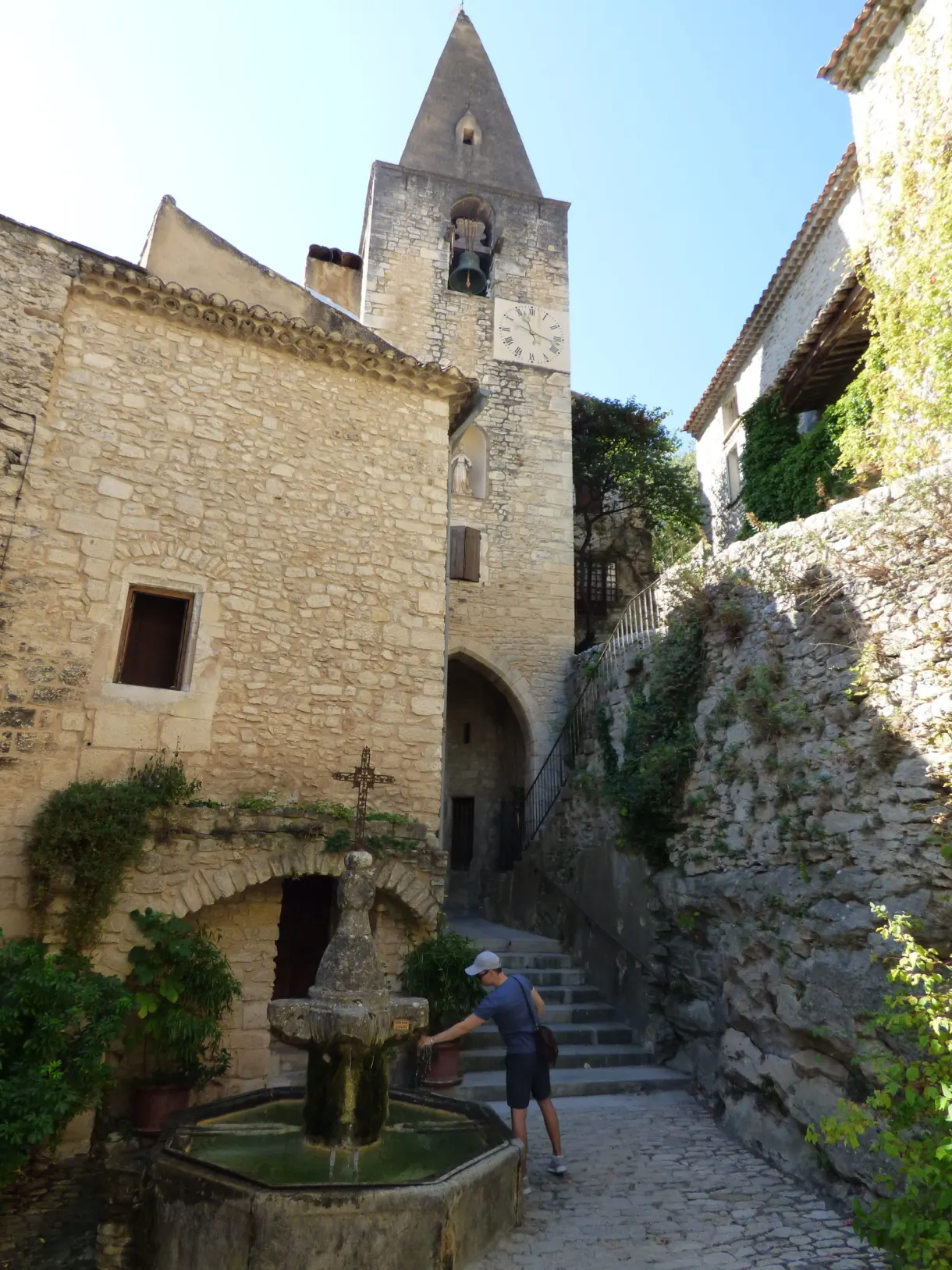 Promeneur à la fontaine devant l'église au clocher-mur