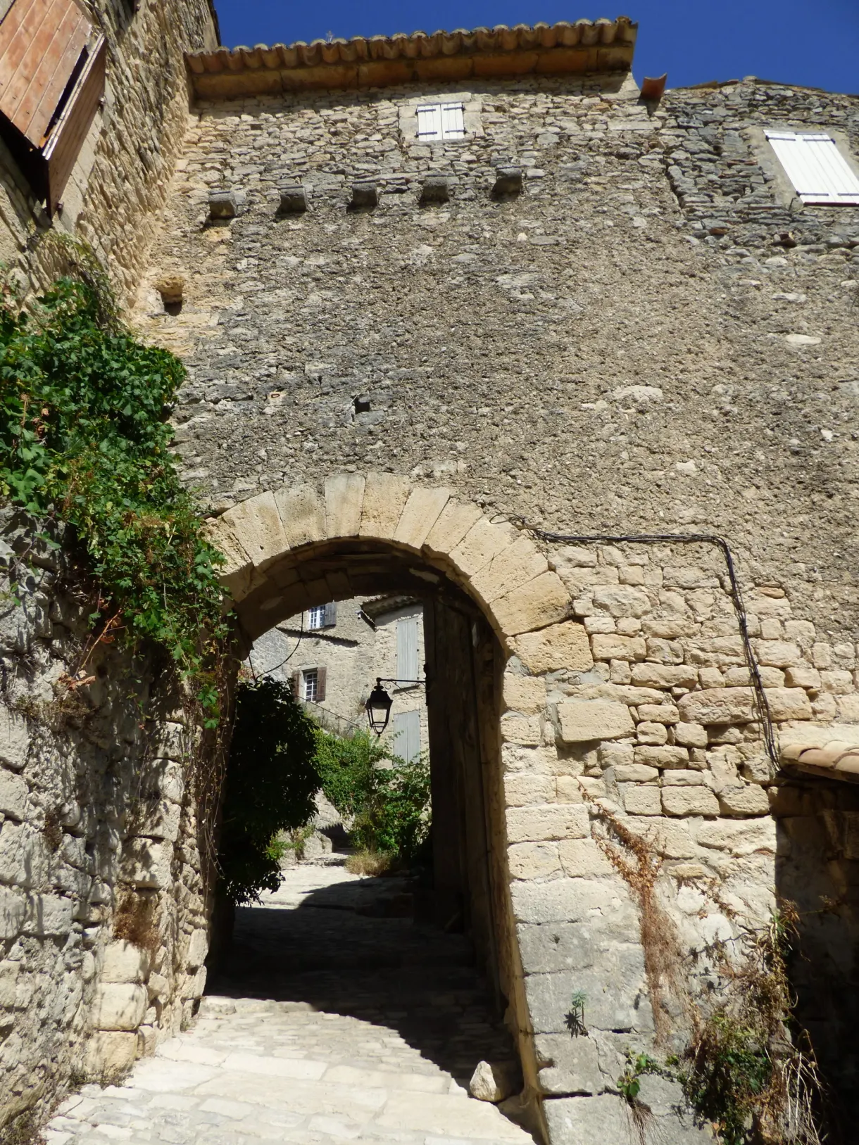 Passage voûté sous une maison, lanterne accrochée à la pierre