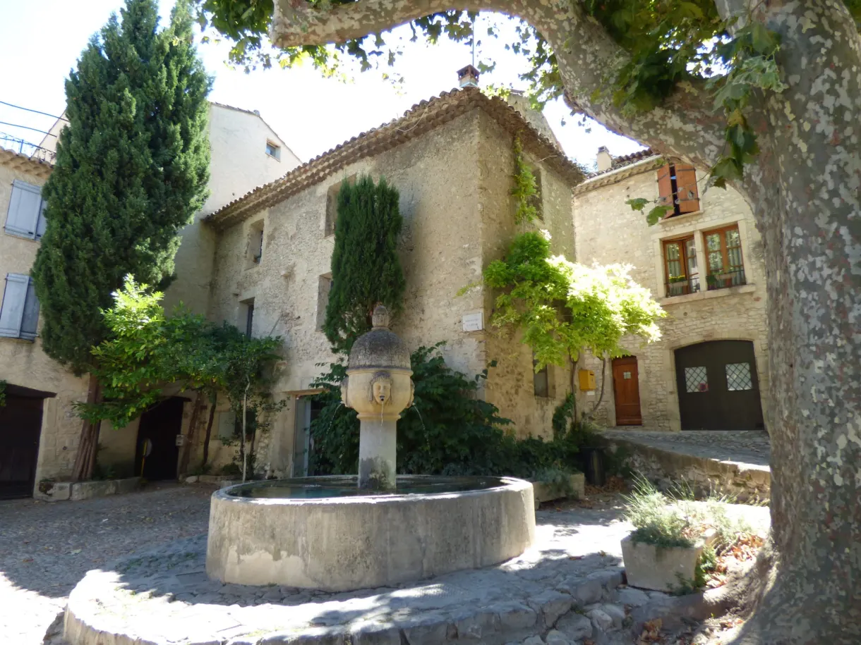 Fontaine circulaire en pierre sur une placette ombragée