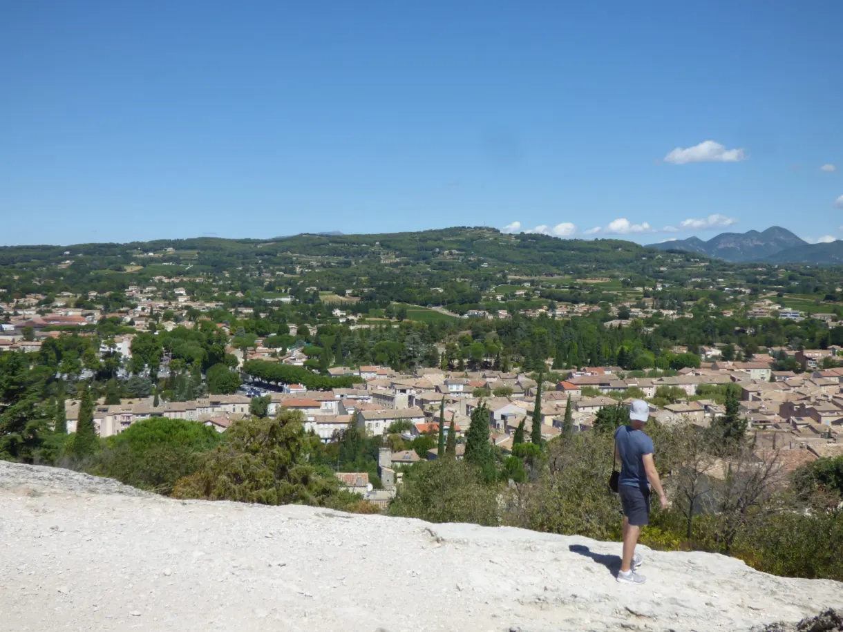 Marcheur sur la dalle rocheuse dominant la plaine et les toits