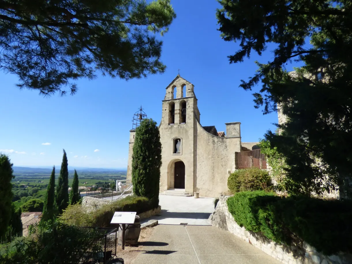 Église à clocher-mur et cyprès dominant la plaine viticole
