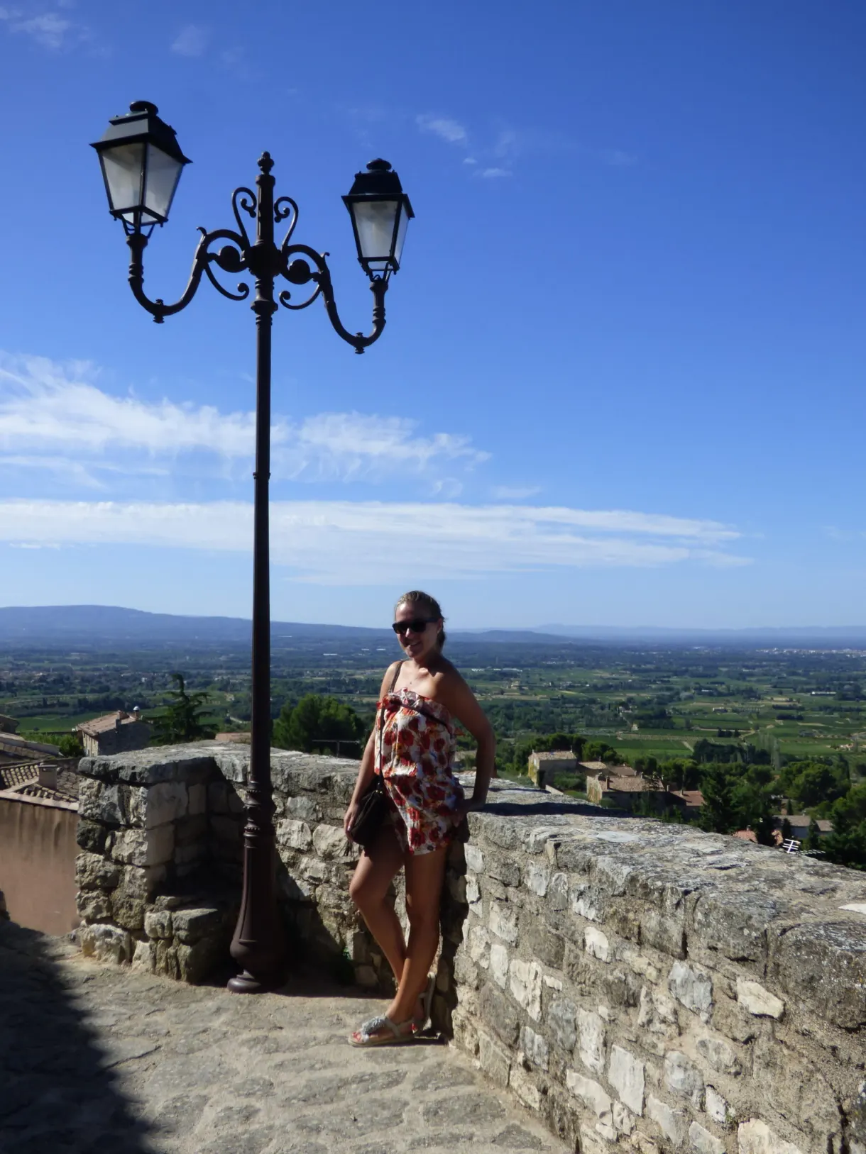 Femme accoudée au parapet sous un lampadaire, plaine en contrebas
