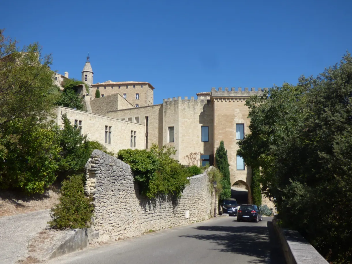 Route montant vers le château entre murets et feuillages