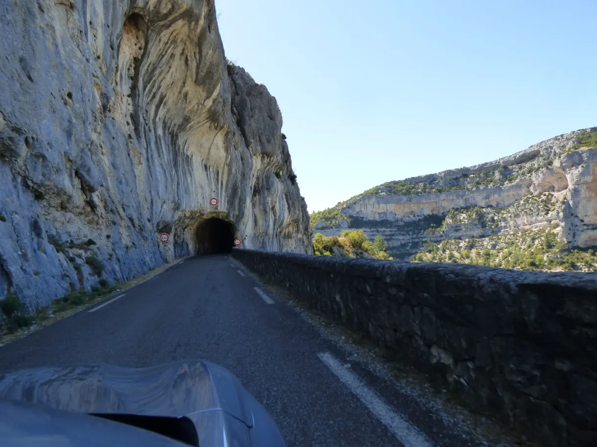 Entrée d'un tunnel taillé dans la roche, vue depuis la route