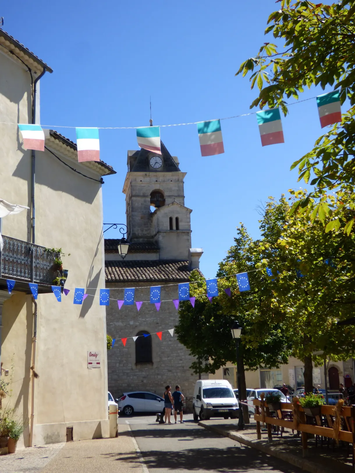 Fanions colorés tendus devant le clocher d'un village animé