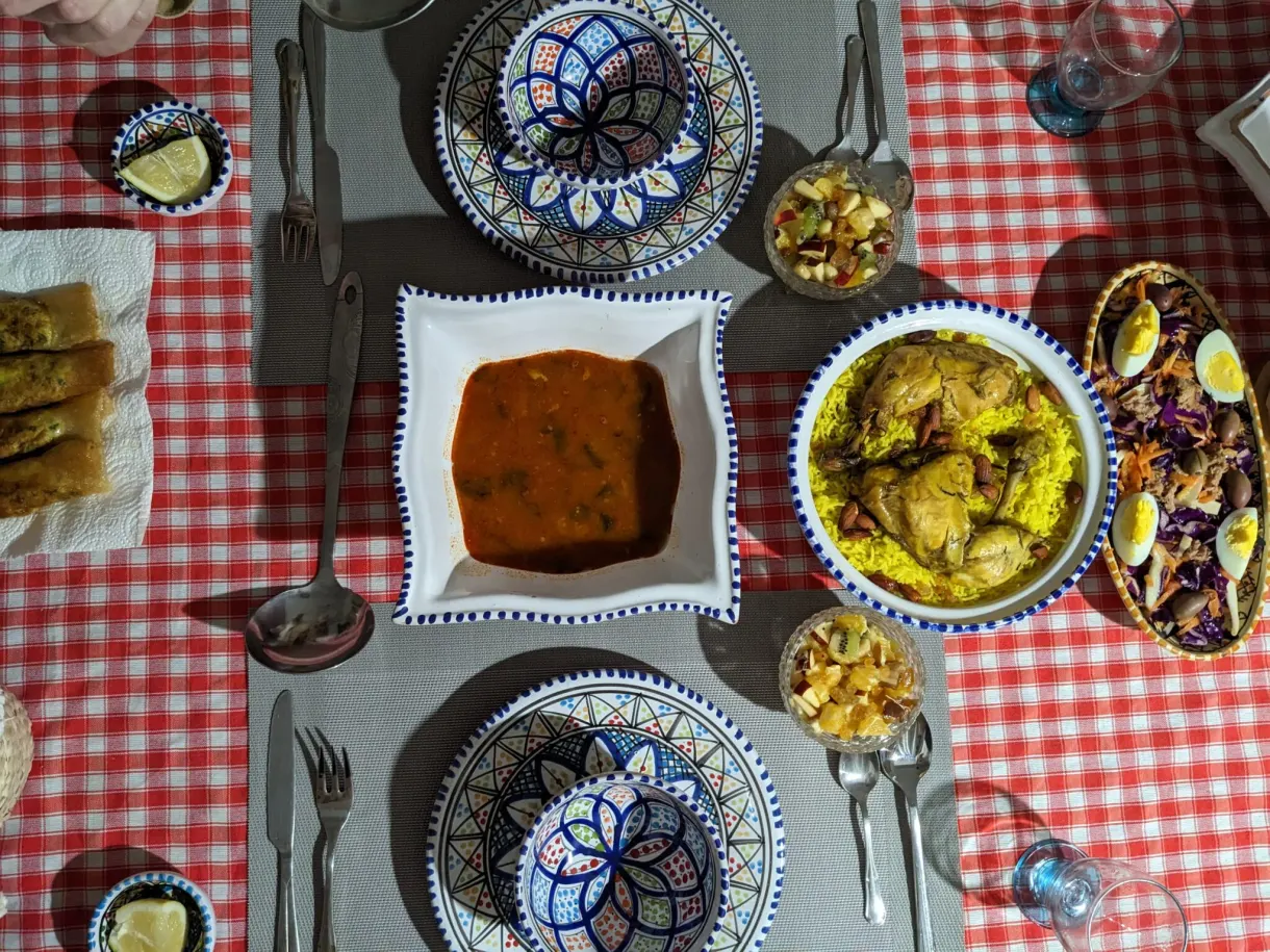 Repas tunisien vu du dessus : poulet au riz, sauce, salade et bricks dans de la vaisselle peinte