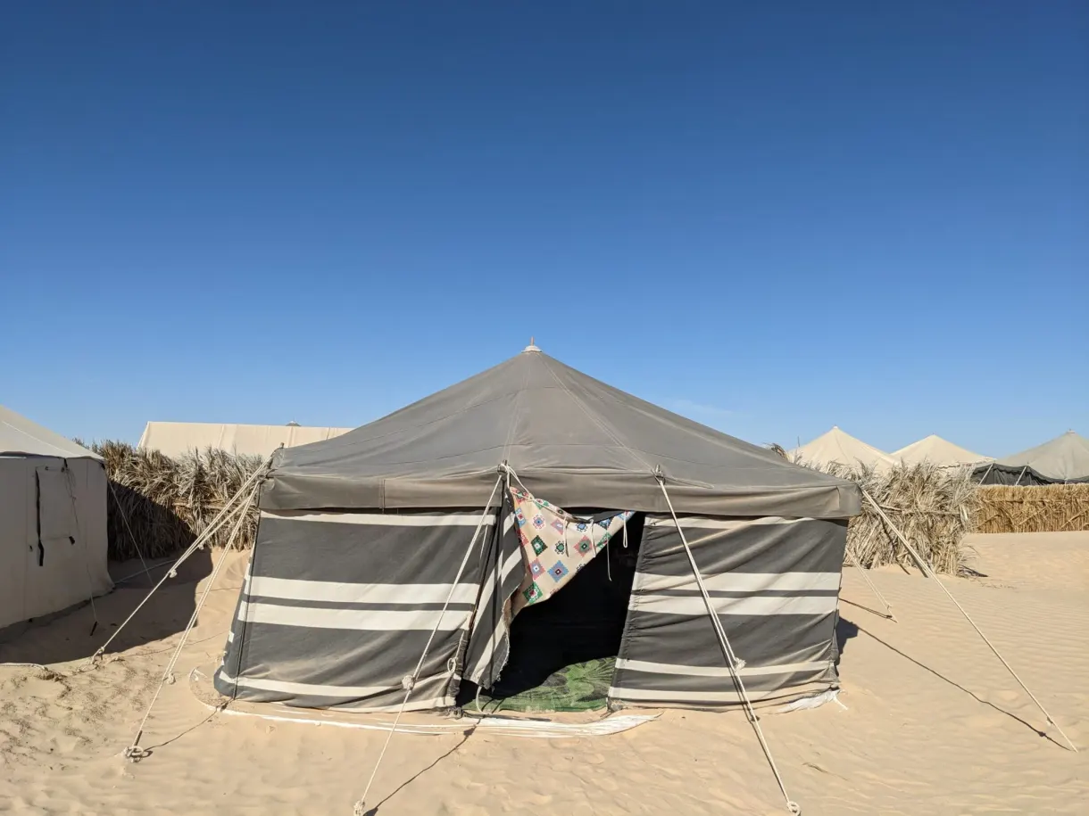 Tente en toile rayée du camp Dunes Insolites, où nous avons dormi dans le désert à Sabria