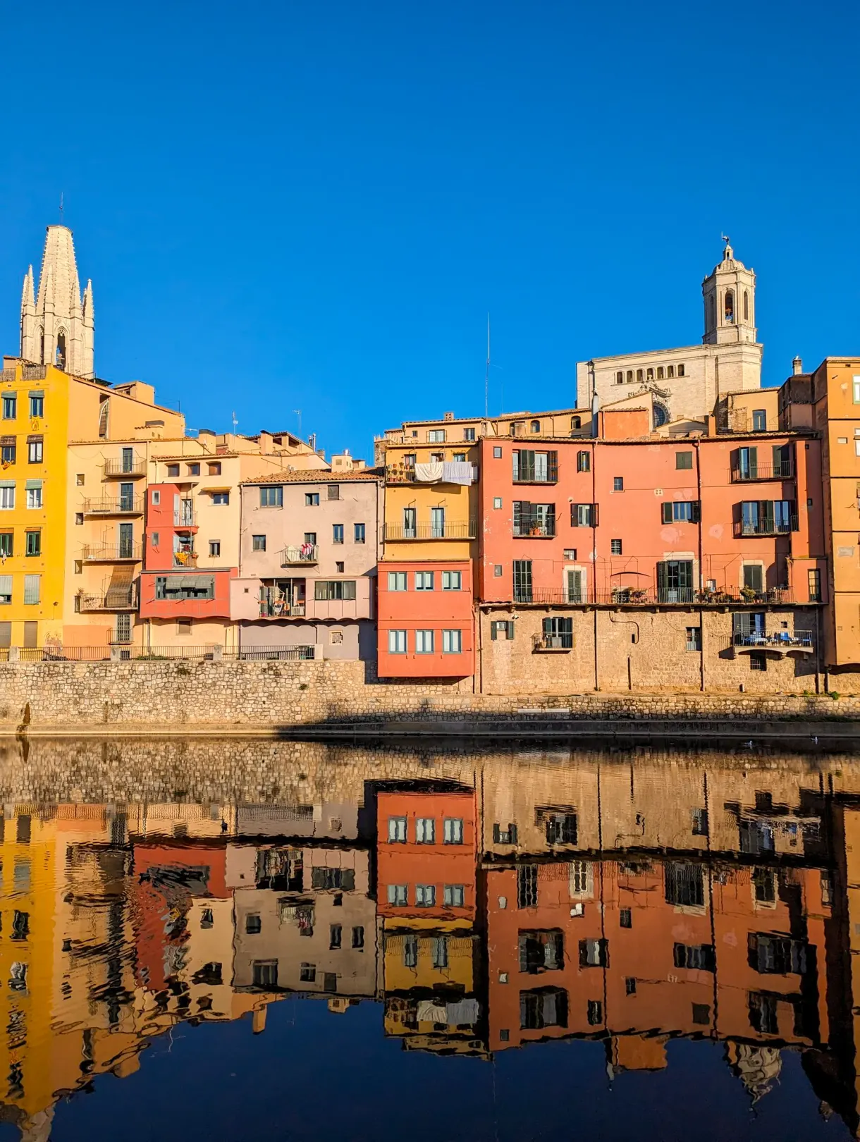 Maisons colorées de Gérone reflétées dans l'Onyar, avec la cathédrale en arrière-plan