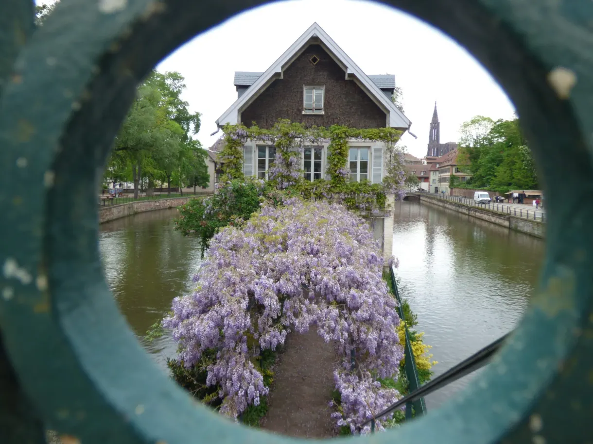Canal et maison fleurie cadrés dans un anneau de métal