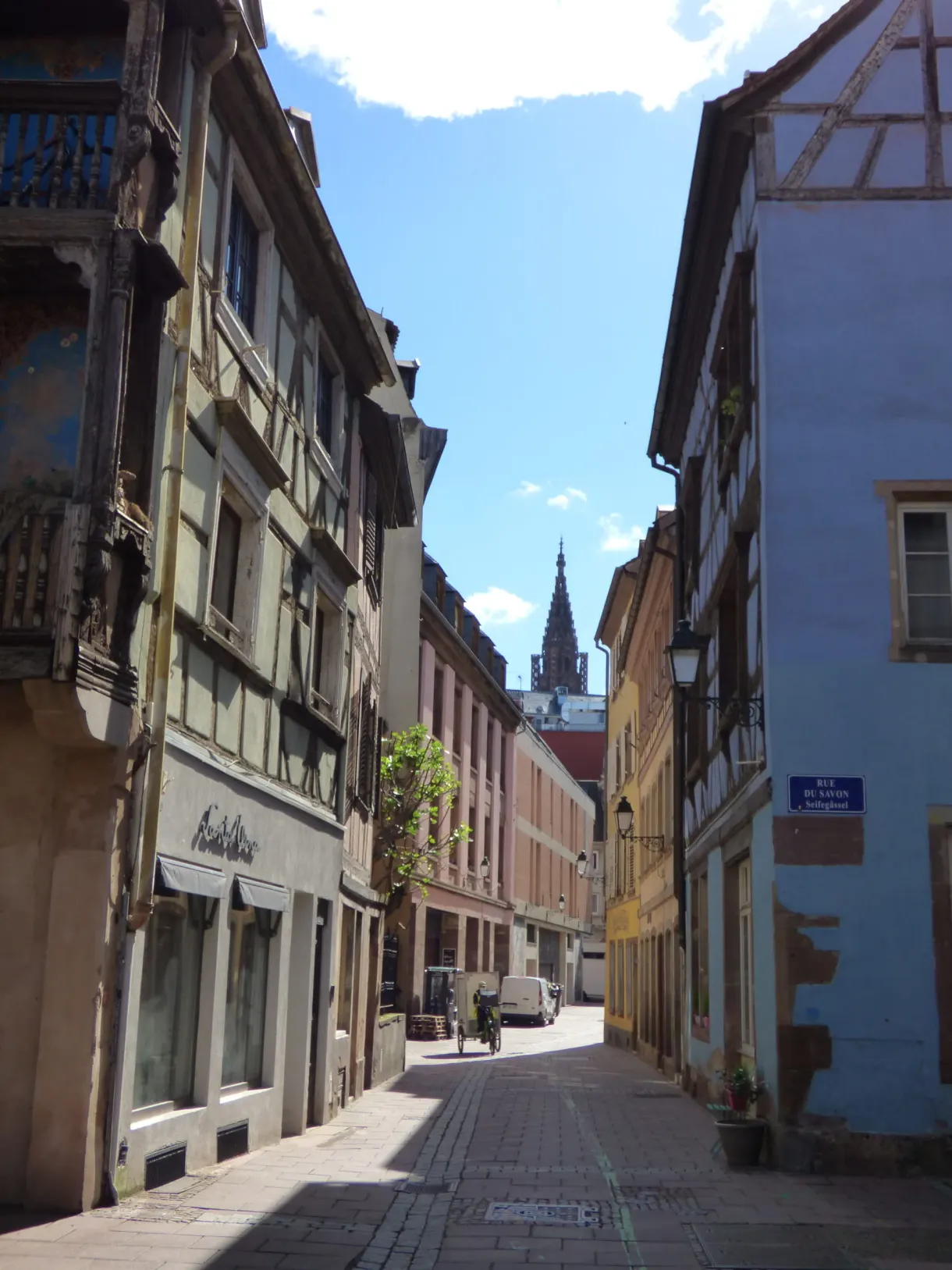 Rue étroite du centre avec une flèche gothique au fond
