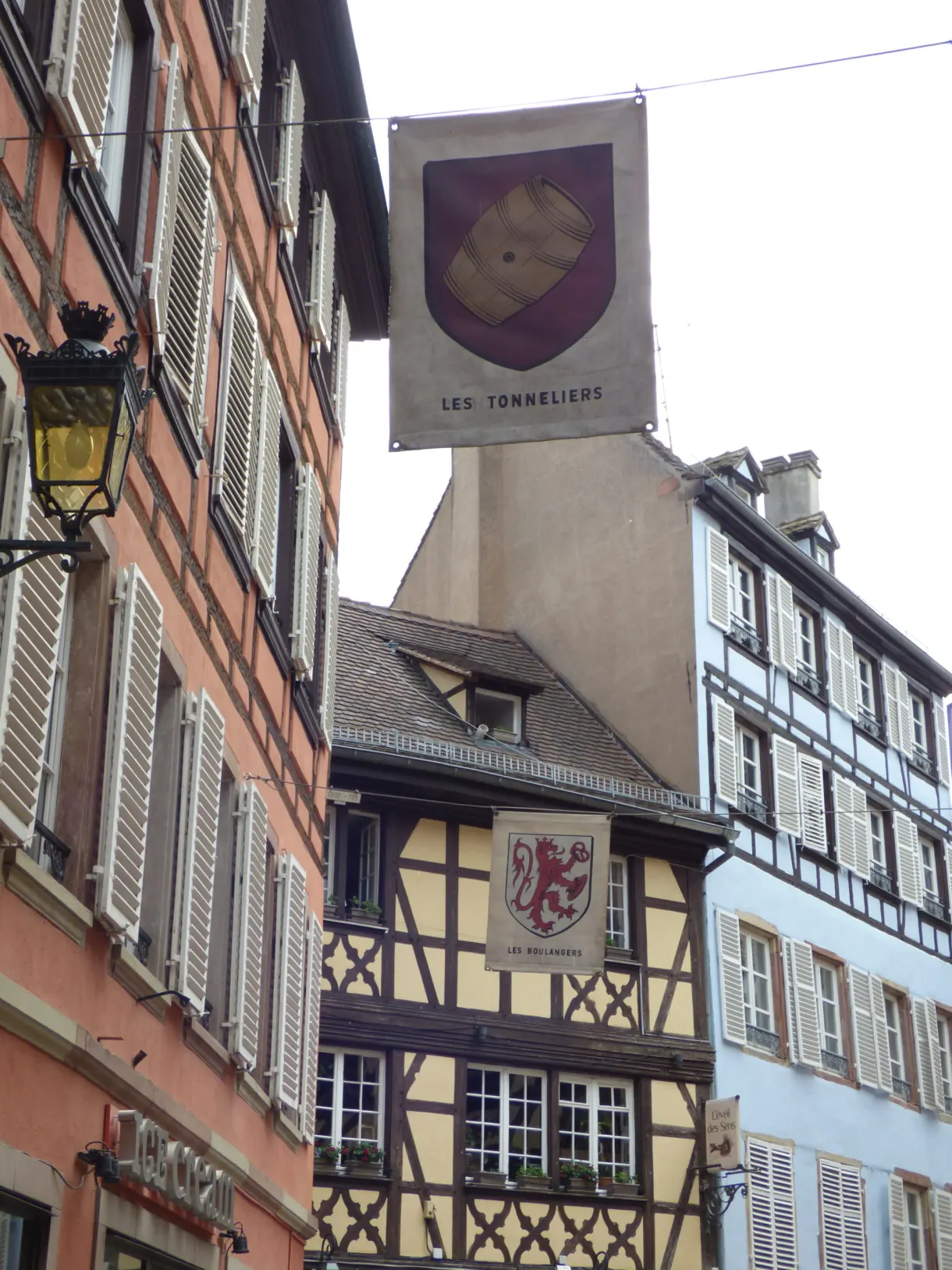 Enseigne peinte de tonnelier suspendue devant une façade rose