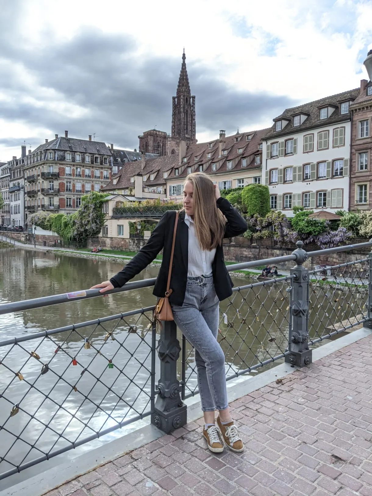 Voyageuse appuyée à une rambarde de quai, cathédrale au loin