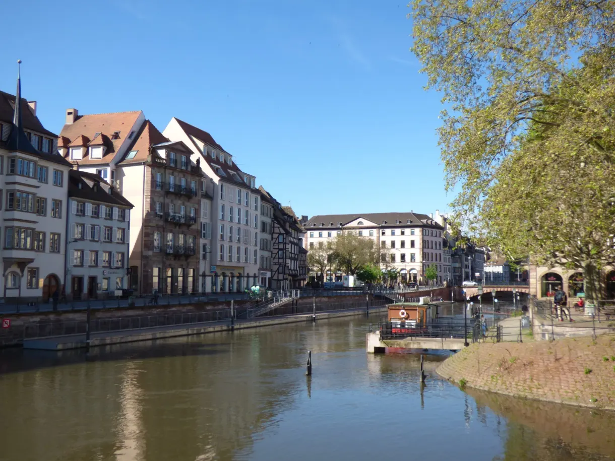 Rivière large entre deux quais d'immeubles, petit bateau au loin