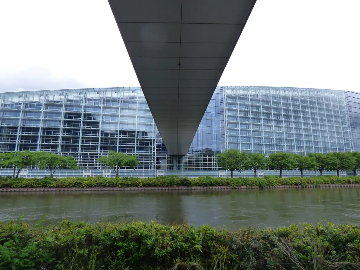 Bâtiments de verre incurvés au bord de l'eau sous un ciel gris