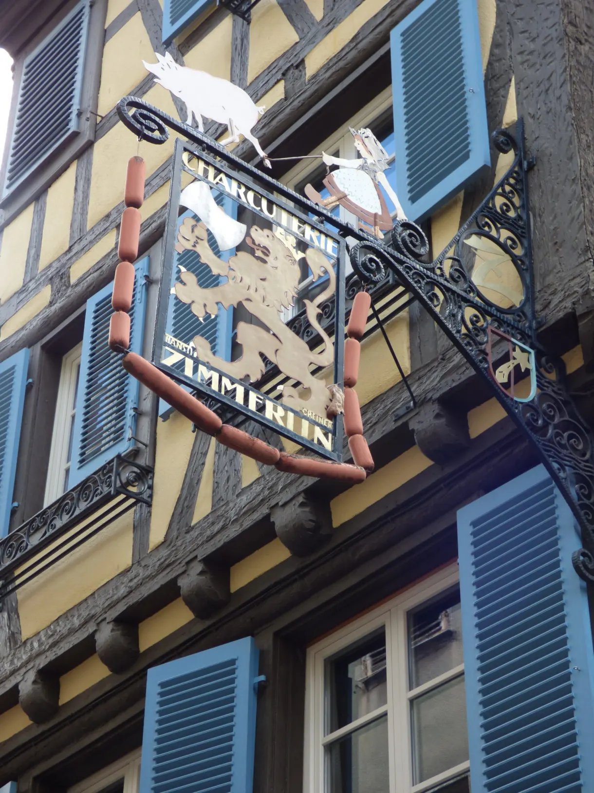 Enseigne en fer forgé de charcuterie ornée de cochons blancs
