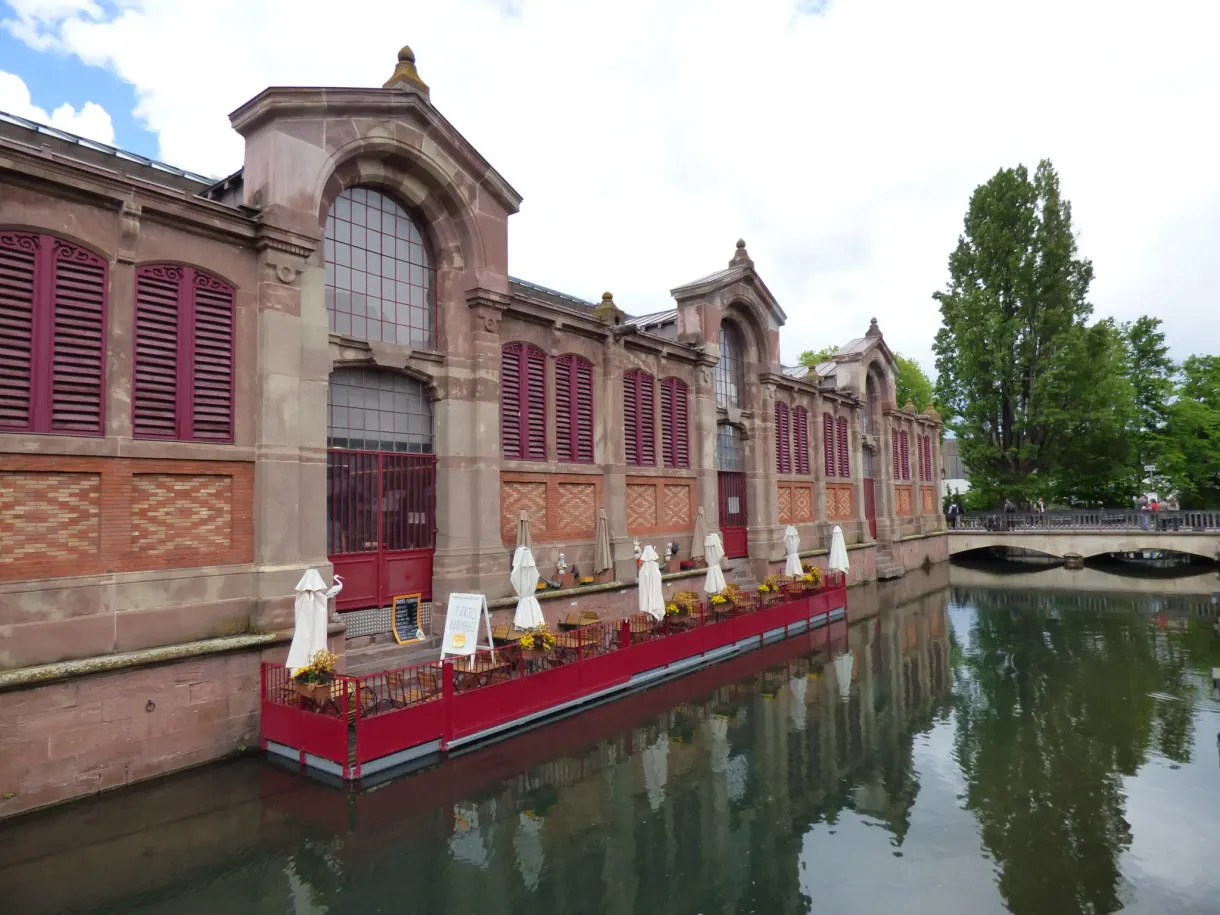 Marché couvert en brique rouge se reflétant dans le canal