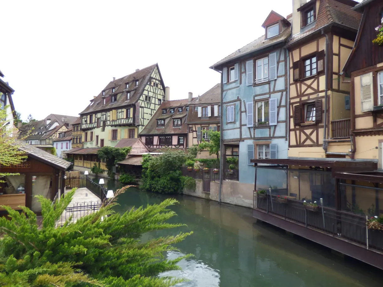 Maisons pastel penchées au-dessus du canal et de sa végétation