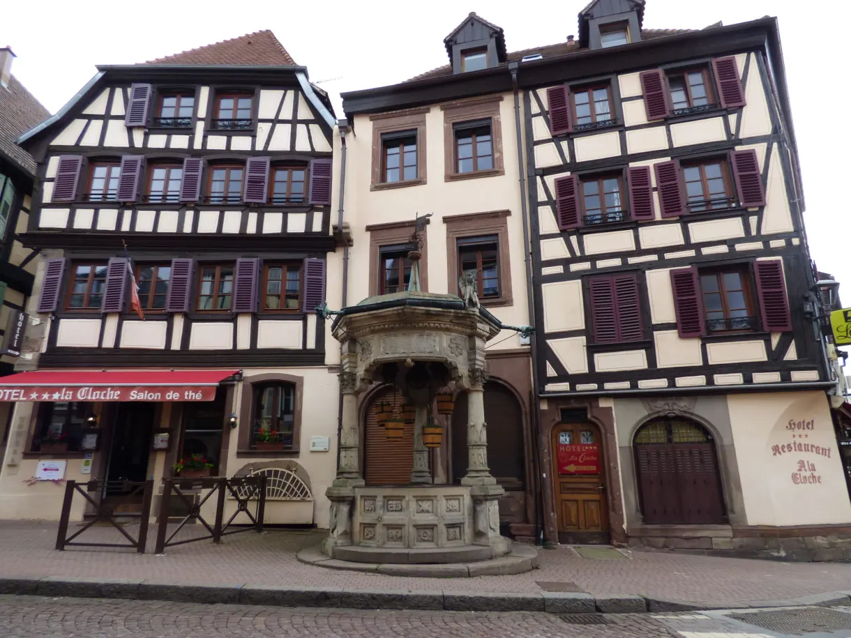 Puits Renaissance sculpté entre deux hautes maisons anciennes