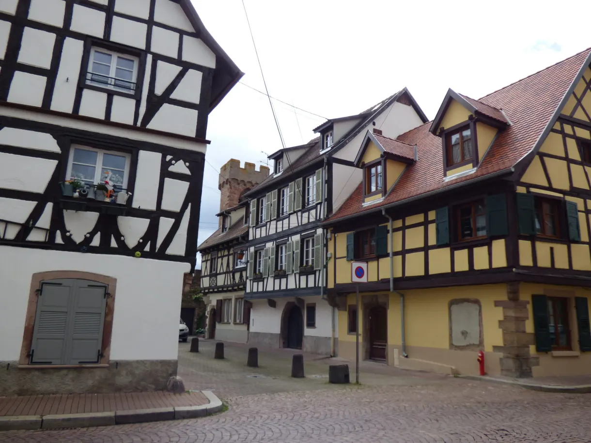 Virage pavé entre des maisons jaunes et blanches à colombages
