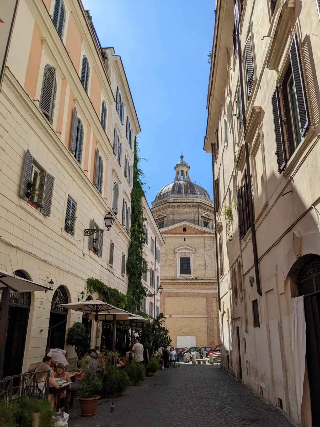 Ruelle bordée de terrasses filant vers une coupole d'église